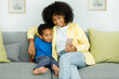 © Home-stock - Little ethnic boy watching cartoons on phone smartphone with mother while sitting on couch at home together