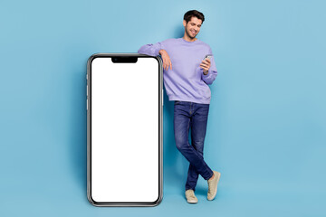 Canvas Print - Full size photo of hr young brunet guy look telephone wear sweater jeans footwear isolated on blue background