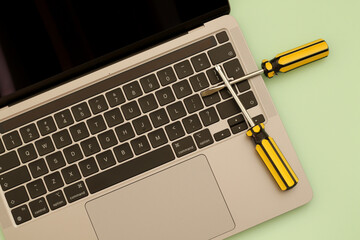 computer repair, laptop and yellow screwdrivers on green background