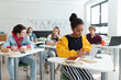 © Halfpoint - High school students paying attention in class, sitting in their desks and writing notes, back to school concept.