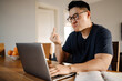Adult angry asian man with laptop showing middle finger gesture