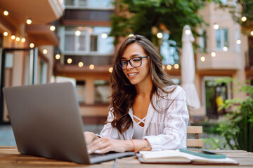 Smiling woman sitting in the cafe and working on laptop. Freelancer, business, online, education concept.