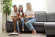 © Angelov - Smiling family pointing at robotic vacuum cleaner