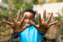 Portrait Of Happy African American Boy Showing Hands In Garden