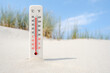 Hot summer day. Celsius and fahrenheit scale thermometer in the sand. Ambient temperature plus 50 degrees