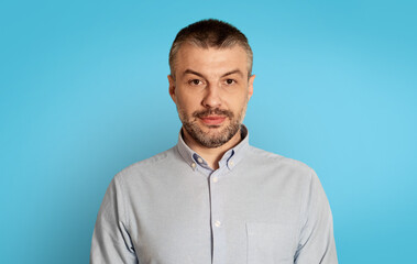 Poster - Portrait Of Serious Middle Aged Man Posing Over Blue Background