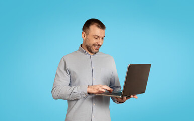 Poster - Happy Middle Aged Male Using Laptop Computer Over Blue Background