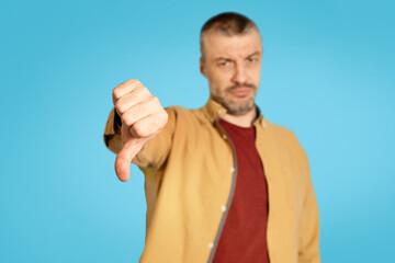 Poster - Discontented Mature Male Gesturing Thumbs Down Disapproving Offer, Blue Background