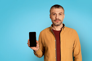 Poster - Serious Man Showing Smartphone With Empty Screen On Blue Background