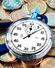 Analog stopwatch and pile of gold coins on a black background close-up. Counting time by stopwatch. Time measurement. Time management concept.A tool for measuring time.Dial stopwatch arrow