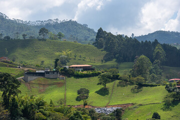 Wall Mural - farm on a hill on a hill with a mountain in the background with trees. Colombia