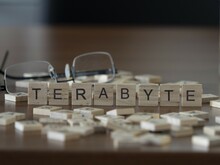 Terabyte Word Or Concept Represented By Wooden Letter Tiles On A Wooden Table With Glasses And A Book