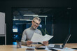 Happy and smiling mature businessman behind paper work, gray haired boss working with accounts and documents, man working in modern office, successful investor reviewing financial reports