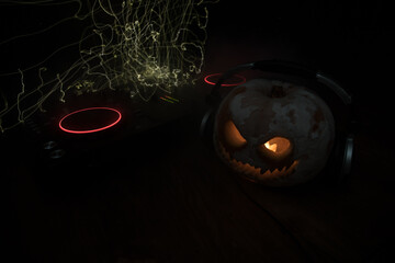 Wall Mural - Halloween pumpkin on a dj table with headphones on dark background with copy space. Happy Halloween festival decorations