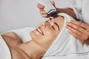Wall Mural - close-up portrait of a woman face getting ultrasound apparatus facial cleaning at beauty salon. hard
