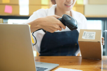 Young asian businesswoman use bar code scanner Scan the barcode on the product box.