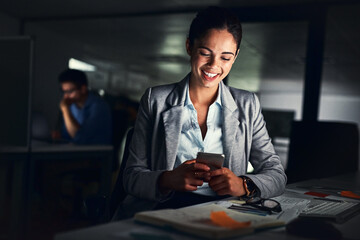 Leinwandbilder - Woman reading text late on phone, smiling at a message and looking at social media posts online while working in a dark office at night. Happy corporate worker checking emails and doing overtime