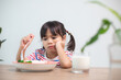 Nutrition & healthy eating habits for kids concept. Children do not like to eat vegetables. Little cute girl refuses to eat healthy vegetables.