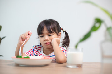 Nutrition & healthy eating habits for kids concept. Children do not like to eat vegetables. Little cute girl refuses to eat healthy vegetables.