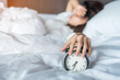 © Jo Panuwat D - Asian woman lying in bed at morning with retro alarm clock, young female sleep in bedroom at home. restless, insomnia sleeping, worried and stressed concepts