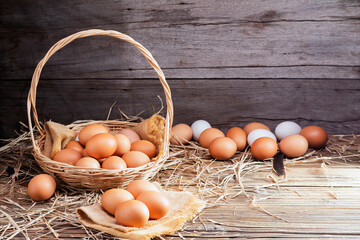 Chicken eggs are laid on the ground and put in a basket on a wooden table on, a rural farm