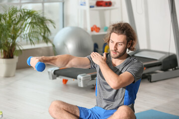 Poster - Sporty young man training with dumbbells  in gym