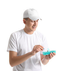 Wall Mural - Young man holding container with pills on white background