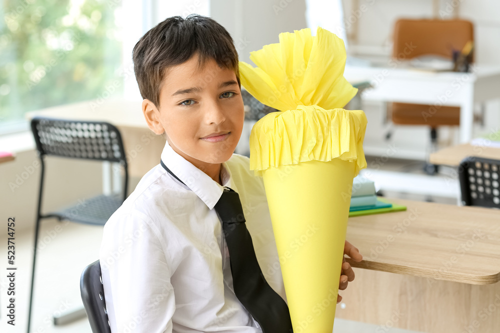 Little boy with yellow school cone in classroom