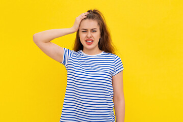 Shocked young woman forgot, remember smth, slap forehead and gasping startled, realize something, standing in white-blue striped t shirt over yellow background