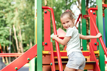 Wall Mural - Caucasian little girl playing at playground in summer day