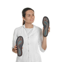 Wall Mural - Beautiful female orthopedist showing insoles on white background