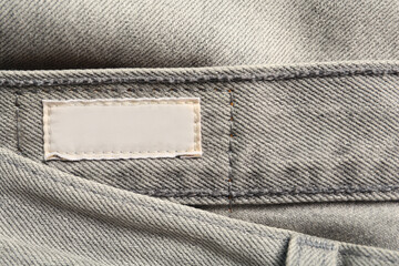 Wall Mural - Blank clothing label on grey jeans, top view