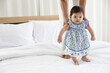 © offsuperphoto - baby girl learning to walk and mother or sitter support her on bedroom