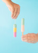 © Anita - Creative aesthetic arrangement made of hands holding fruit ice creams on a blue background. Minimal summer concept.