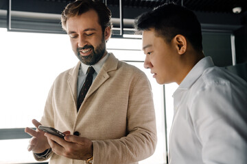 Wall Mural - Adult multiracial businessmen talking and using cellphone in office