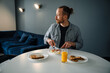 © Drobot Dean - Young man having breakfast while sitting at table at home