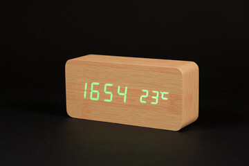 Wall Mural - Electronic digital wooden clock with thermometer on a black background close-up.