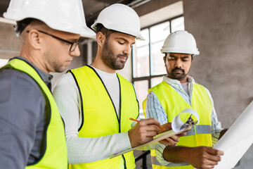 Wall Mural - architecture, construction business and people concept - male architects in helmets with clipboard discussing blueprint in office building