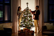 © Syda Productions - winter holidays and people concept - happy couple decorating christmas tree at home