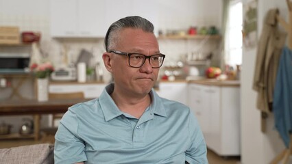 Wall Mural - worried Japanese mature man having headache while considering hard decision alone at home. he stares into distance and shakes head feeling stressed out