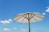 Fototapeta Tęcza - umbrella and sky, Summer,White beach umbrella, background with blue sky and white clouds on a sunny day.