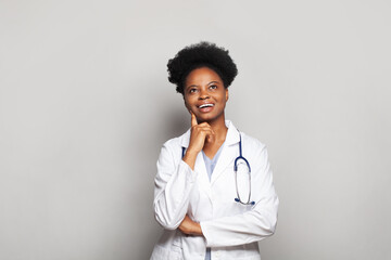 Wall Mural - Attractive black woman doctor in white uniform looking up on white banner background