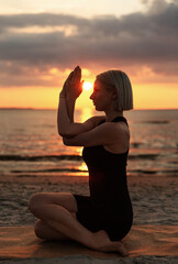 Poster - fitness, sport, and healthy lifestyle concept - woman doing yoga seated eagle pose on beach over sunset