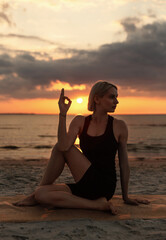 Canvas Print - fitness, sport, and healthy lifestyle concept - woman doing yoga half lord of the fishes pose on beach over sunset