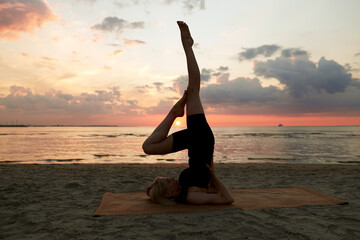 Poster - fitness, sport, and healthy lifestyle concept - woman doing yoga shoulderstand on beach over sunset