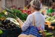 © luciano - Back view of senior woman choosing fresh vegetables at the green farmers market, price increase and inflation