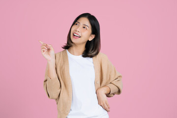 Asian woman standing isolated pink background. She pointed to the empty side.