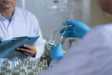 Product quality control officer in fruit juice production line Carry out an inspection of bottles used to contain fruit juices