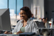 © supamotion - African American female employee working at her desk in the office located in a skyscraper. Modern friendly working environment