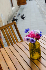 Sticker - Cornflowers colored blue and pink bouquet in a brown glass bottle on a nine background.